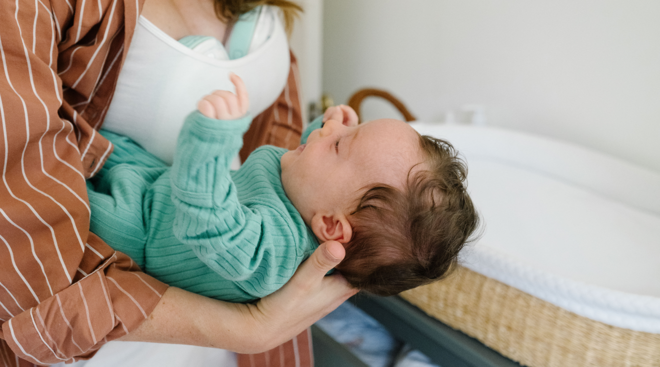 mom using wearable breast pump while holding baby