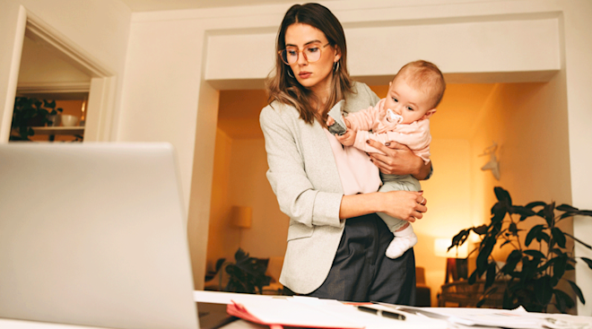 mom holding baby while working at home