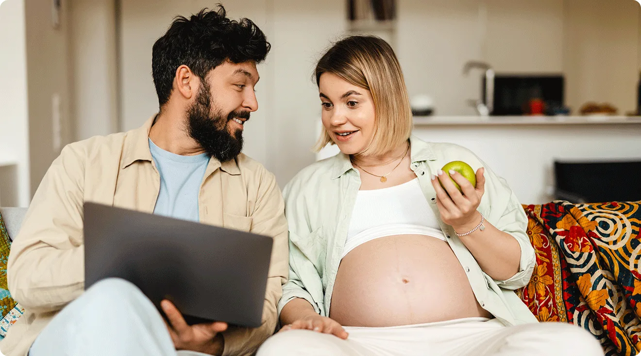 pregnant couple shopping online at home on the couch