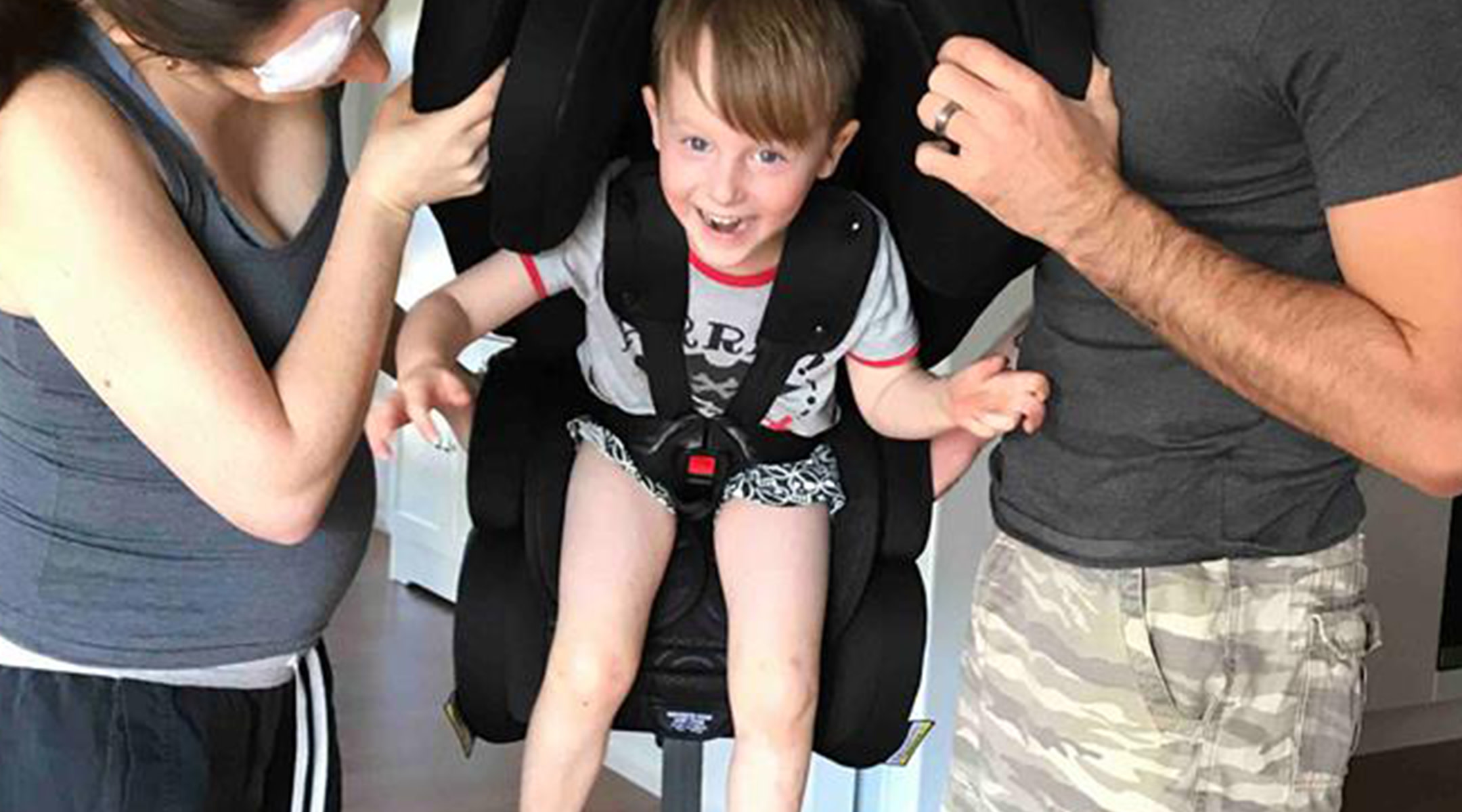 Couple holding their 4-year-old in a car seat