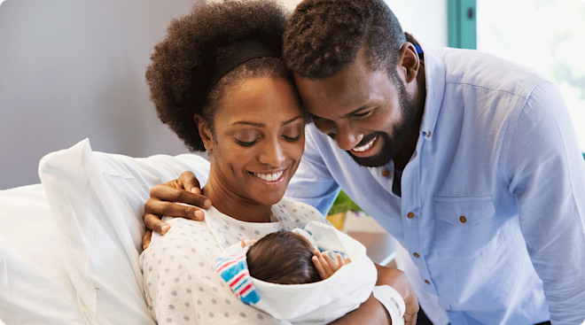 happy parents holding newborn baby in hospital delivery room