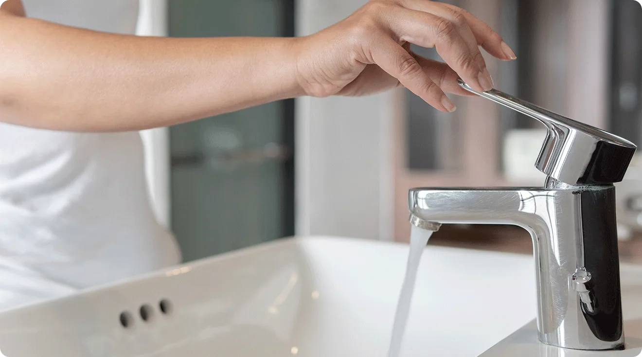 close up of woman turning on water faucet in bathroom
