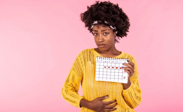 Woman holding calender and clutching her abdomen in pain