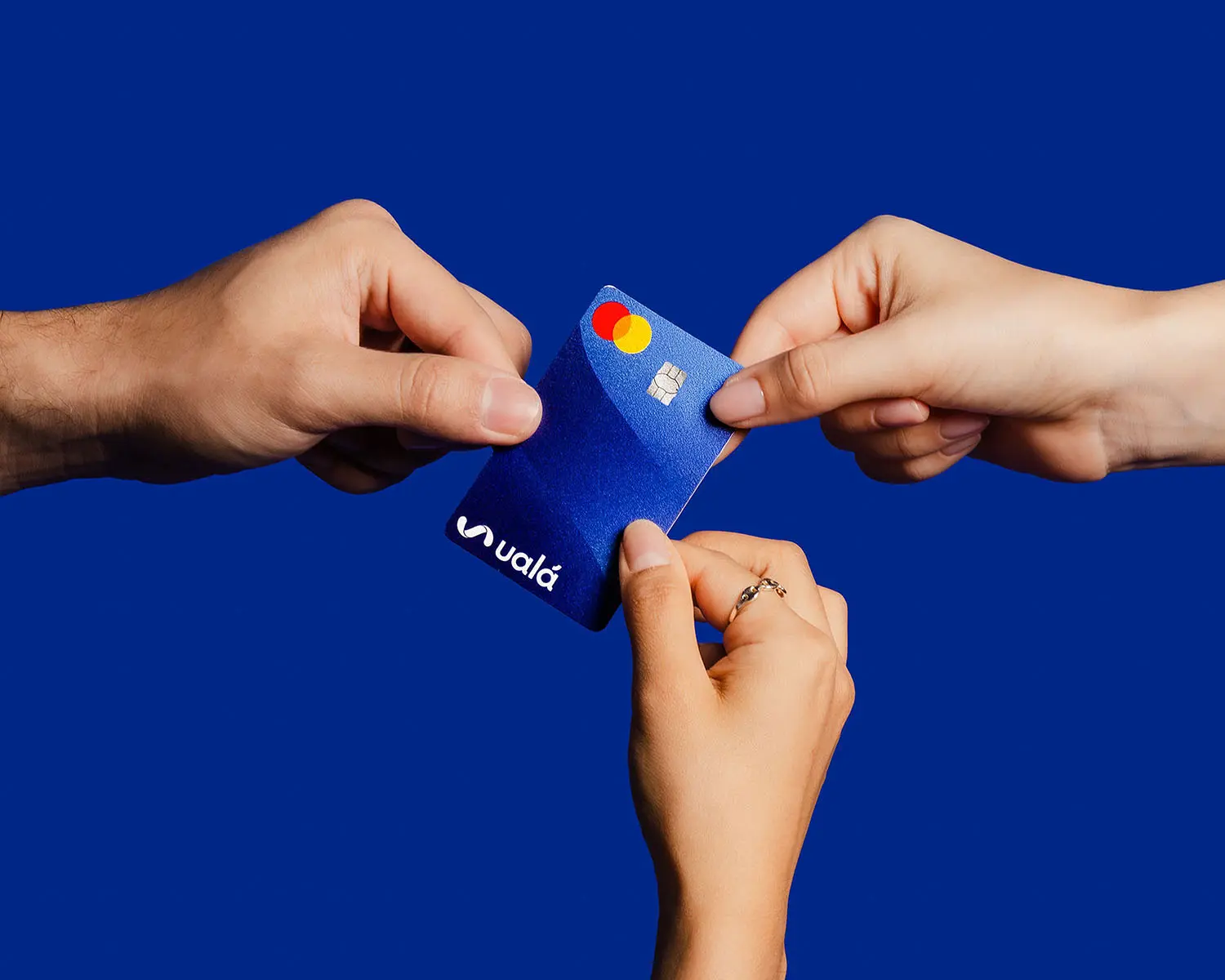 3 manos sosteniendo la tarjeta de crédito de Ualá