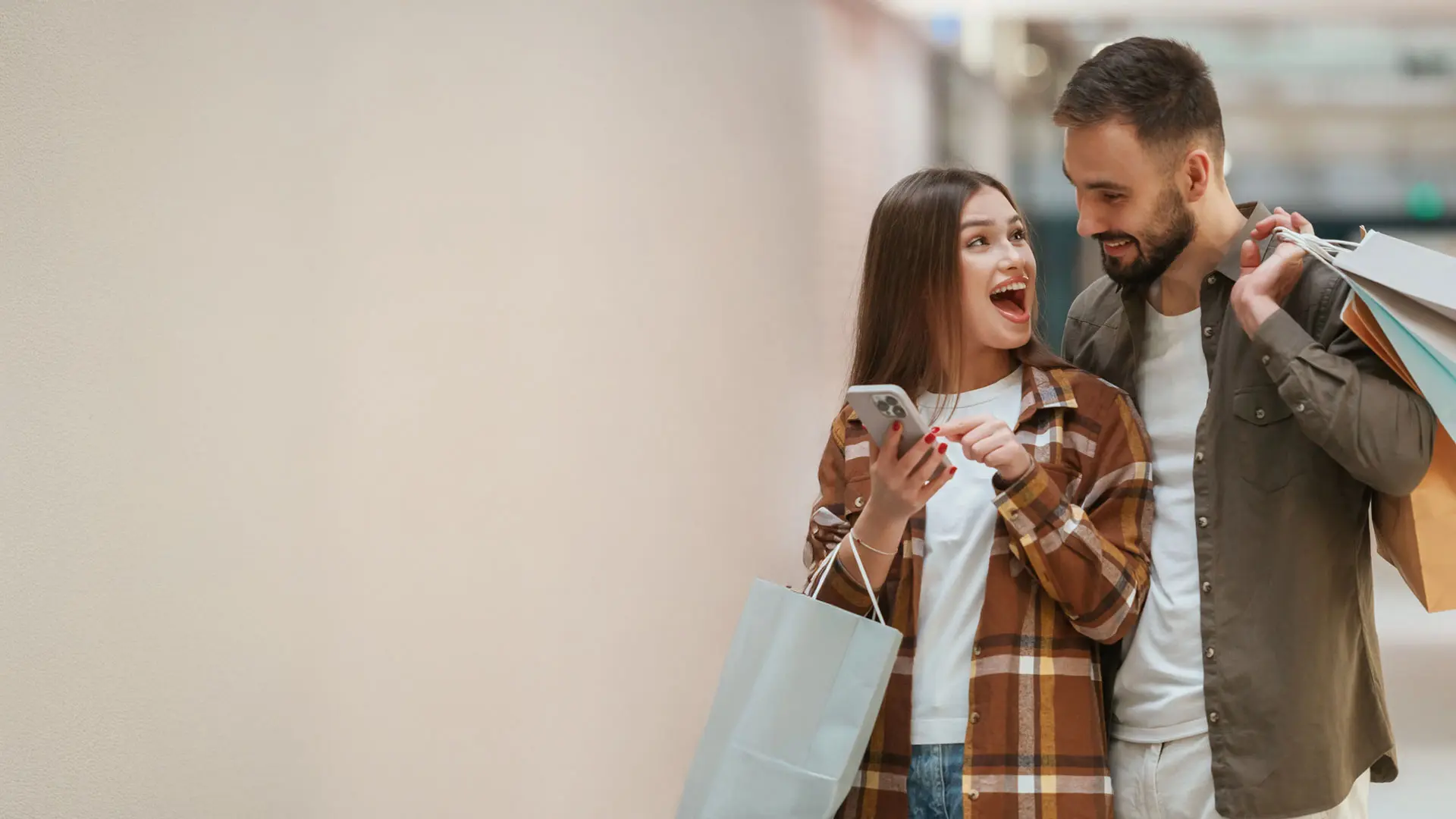 Imagen de una pareja realizando compras y viendo su celular para ver los beneficios de Ualá