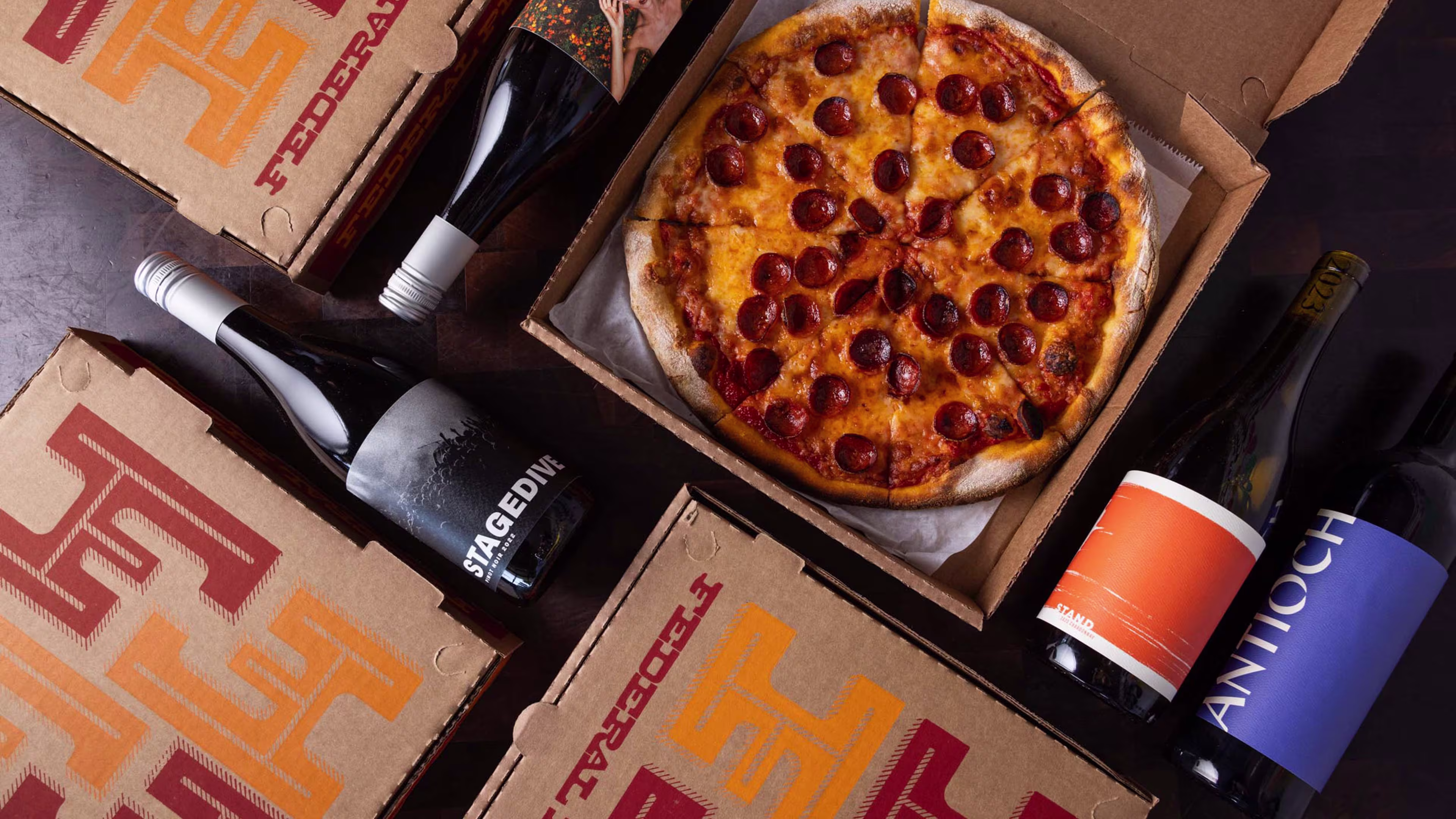 Bottles of Wine on a table with Pizza Boxes