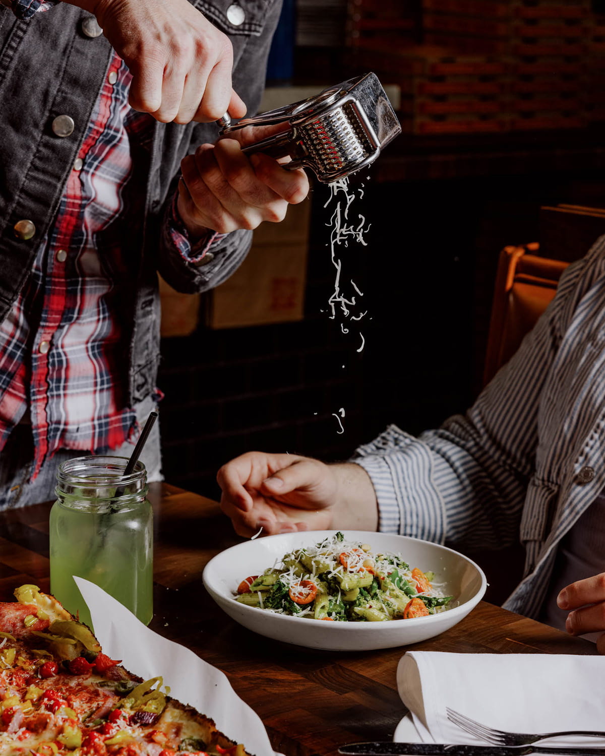 A man shredding fresh parmesan onto a salad