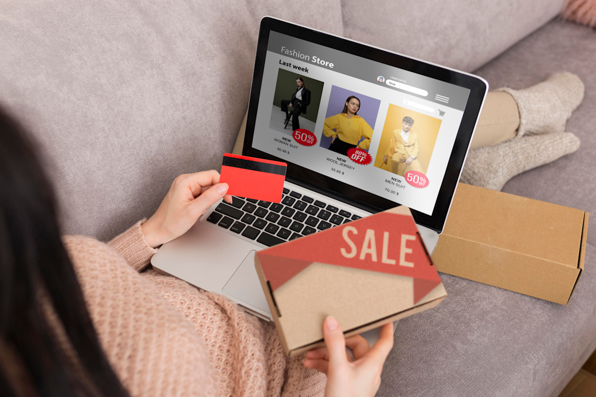 Femme tenant une carte bleue et effectuant un achat en ligne sur un site e-commerce via un ordinateur portable.