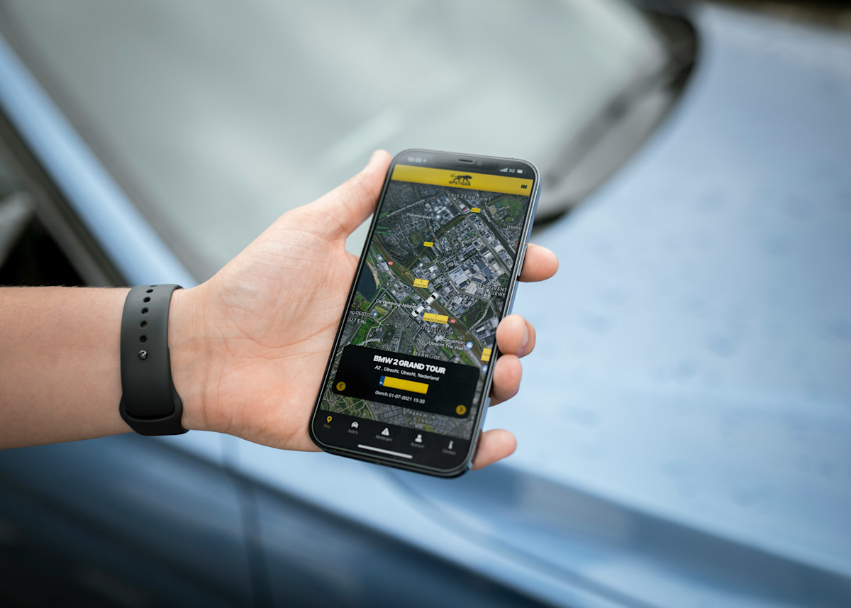 Main tenant un smartphone affichant une application mobile de navigation ou de suivi en temps réel, illustrant l'utilisation d'une app pour localiser un véhicule ou gérer des trajets en mobilité.