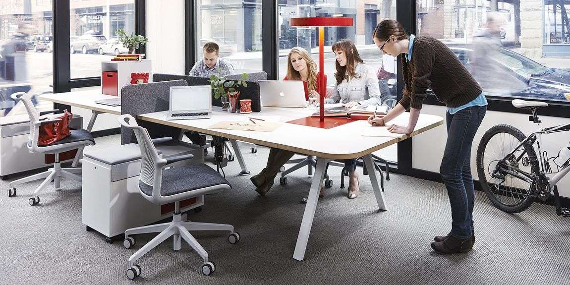 People at work around collaborative desk in front of big windows with light