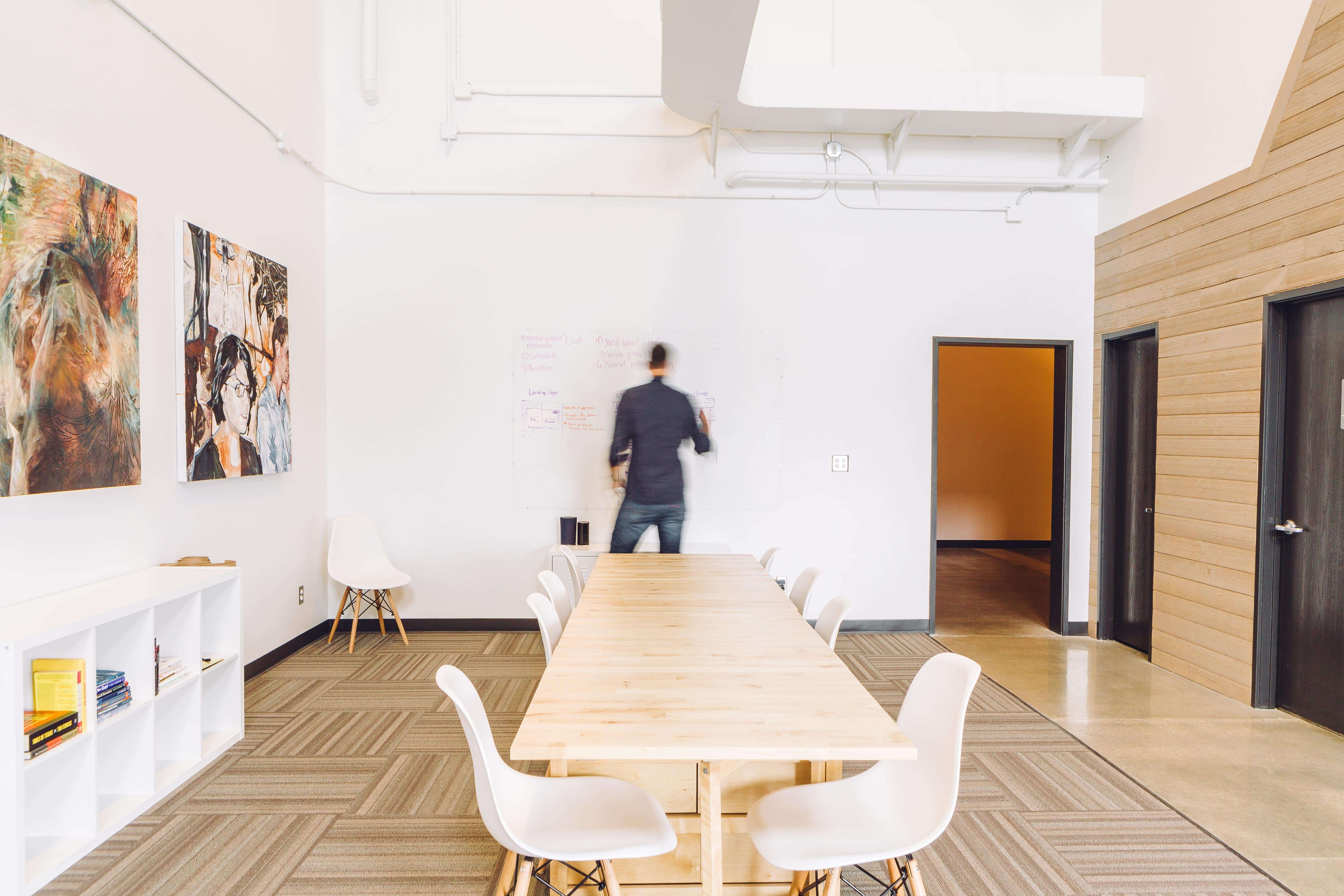 Man facing white board in front of long conference table