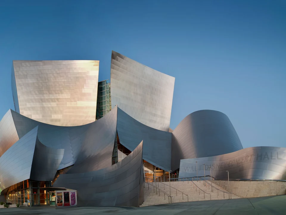 Exterior view of Walt Disney Concert Hall with its unique, curving metal architecture against a clear blue sky.