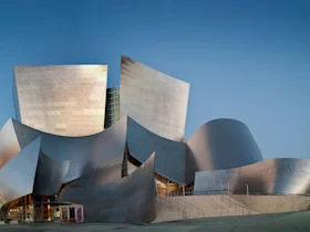 Exterior view of Walt Disney Concert Hall with its unique, curving metal architecture against a clear blue sky.