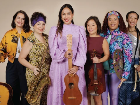 Production shot of Música in NYC, showing a group of performers along with Sonia De Los Santos, the main performer of the show. 