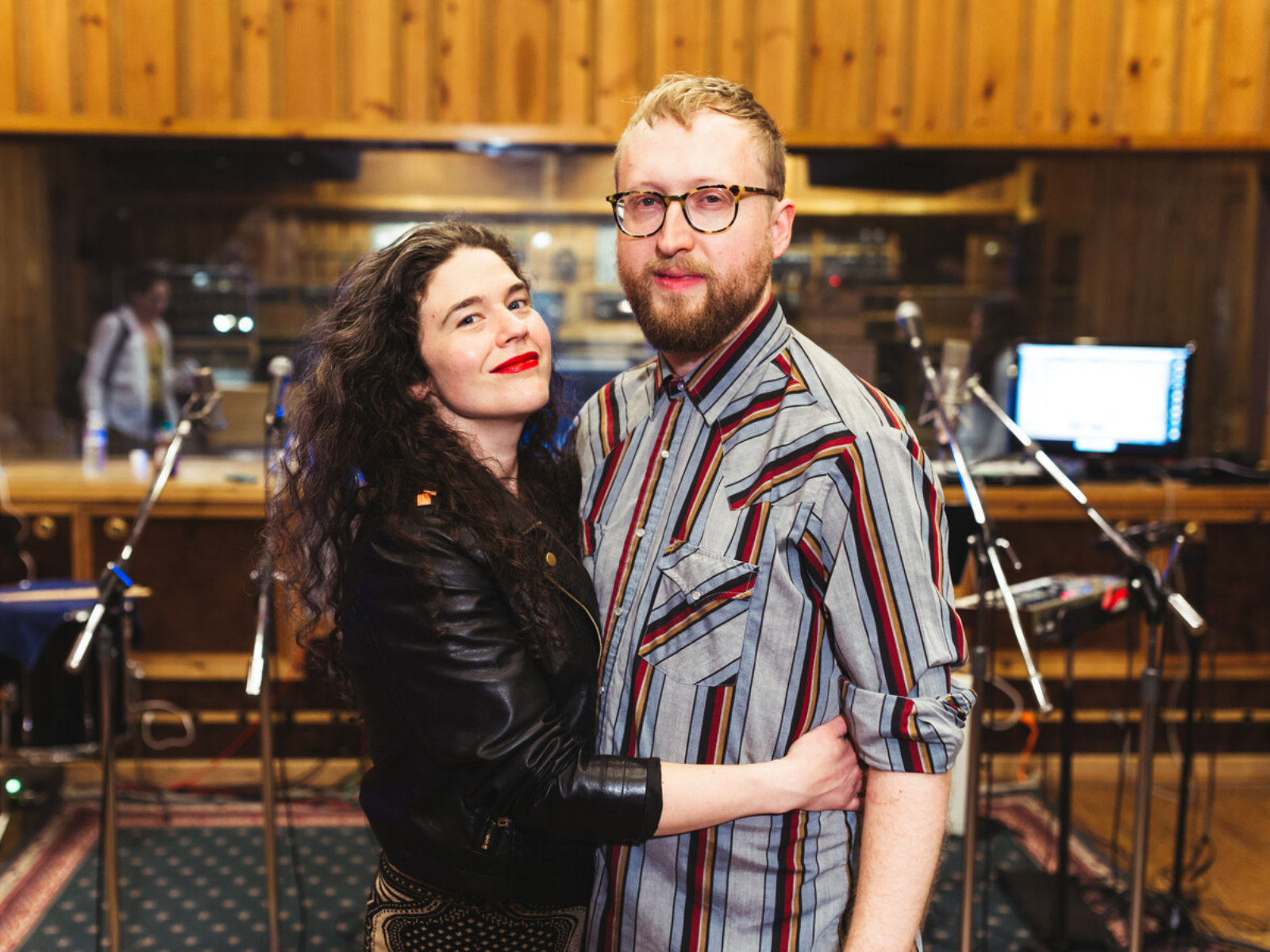 Photo of Abigail and Shaun Bengson as they stand in a recording studio with microphones and music equipment in the background.