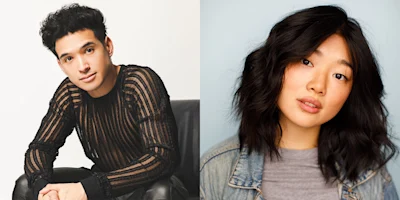 A young man in a sheer black striped shirt sits on a chair; next to him, a young woman with wavy dark hair wears a denim jacket over a gray shirt, both facing the camera.