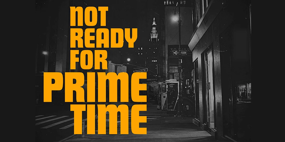 Bold yellow text reads "Not Ready For Prime Time" overlaying a black and white photo of a city street at night with illuminated buildings in the background.