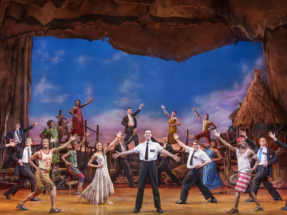 Production image of The Book of Mormon in London featuring the full ensemble cast.