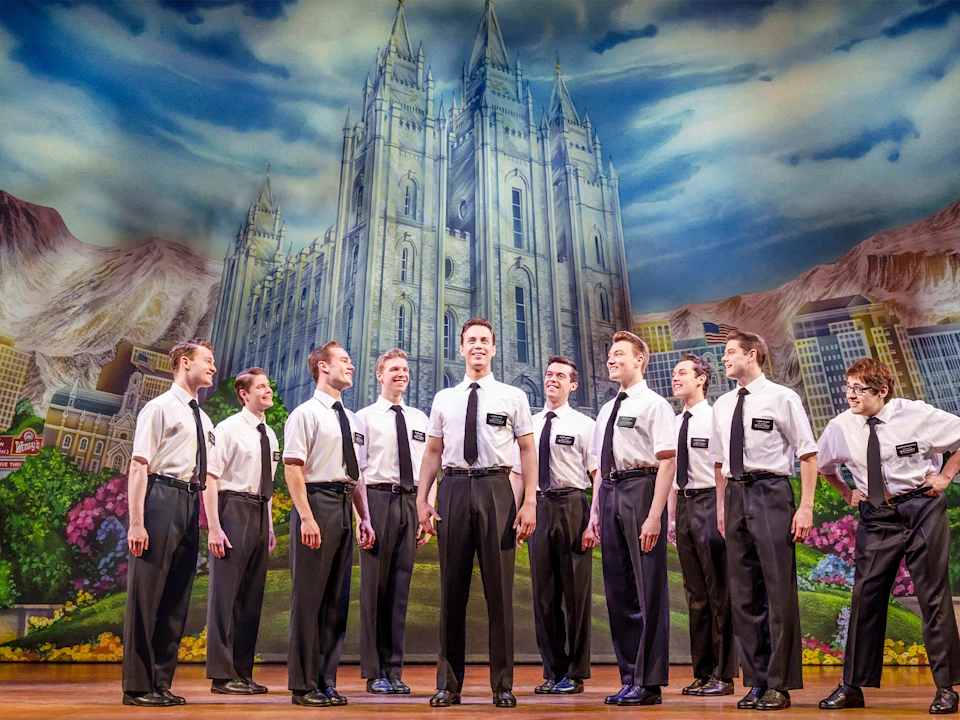 Production image of The Book of Mormon in London featuring the full ensemble cast.