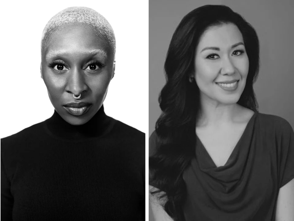 Black-and-white portrait of two women, one with a shaved head and nose ring on the left (Cynthia Erivo), the other with long, wavy hair and a smile on the right (Ruthie Ann Miles).