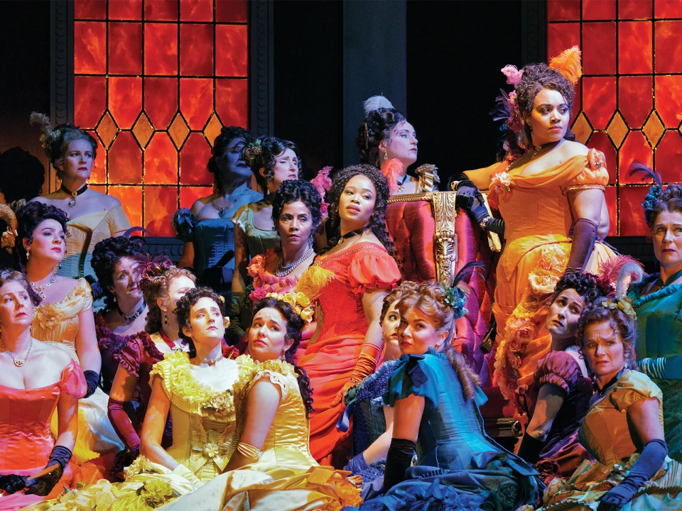 Production shot of La Traviata, showing ensemble performing.