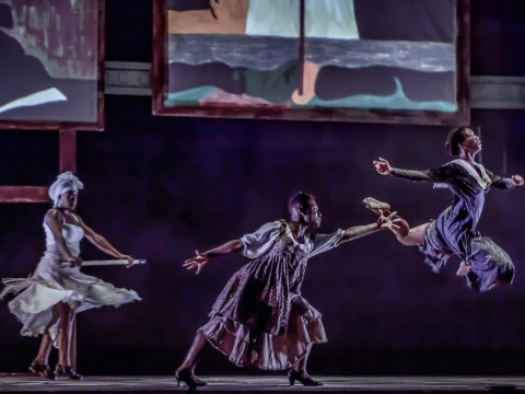 Production photo of The Migration: Reflections on Jacob Lawrence in Washington with three dancers perform on stage in mid-action.