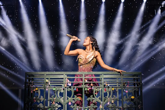 Production photo of & Juliet in New York, shoing Gianna Harris in a sparkly gold and burgundy dress.
