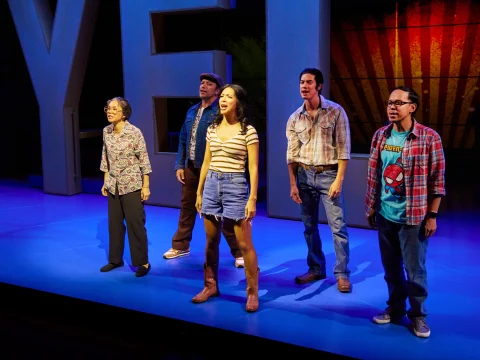 Actors facing the audience in front of giant letters spelling "Yella."