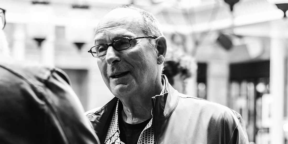 A man with glasses speaking to someone off-camera.