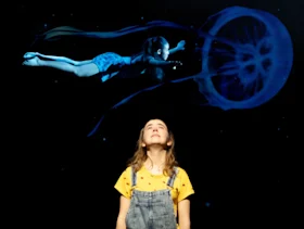 Close-up of a blue eye, with the reflection of an ocean and planet visible in the iris.