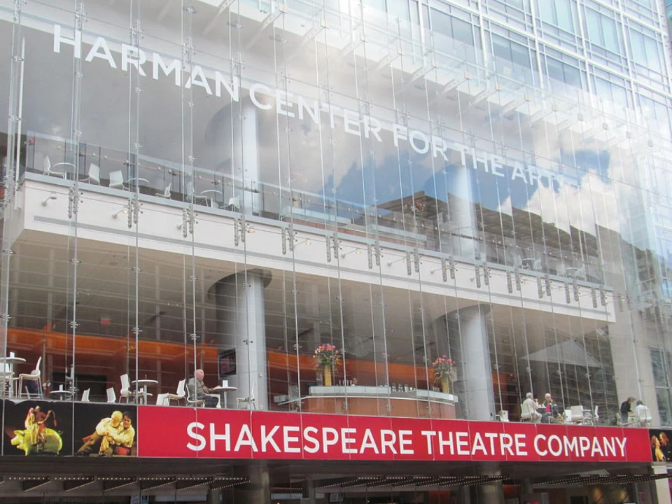 Exterior of the Harman Center for the Arts showcasing modern glass architecture with "SHAKESPEARE THEATRE COMPANY" banner at the entrance.