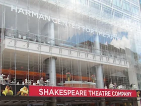 Exterior of the Harman Center for the Arts showcasing modern glass architecture with "SHAKESPEARE THEATRE COMPANY" banner at the entrance.