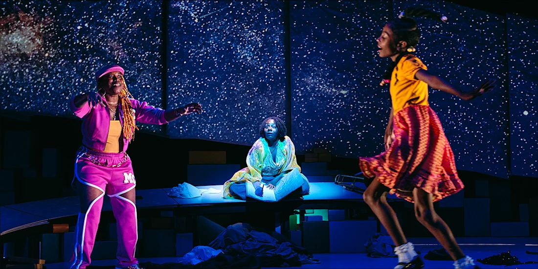 Three actors performing on a stage with a starry night background.