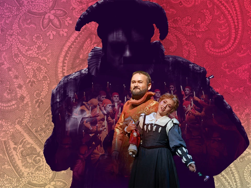 A man and a woman in period costumes perform on stage, with a large, shadowy figure in a horned costume looming in the background against a colorful, patterned backdrop.