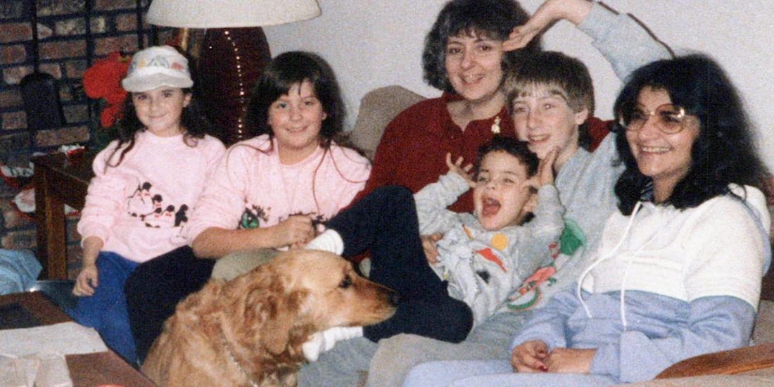 A family sitting together on a sofa with a golden retriever in the foreground.