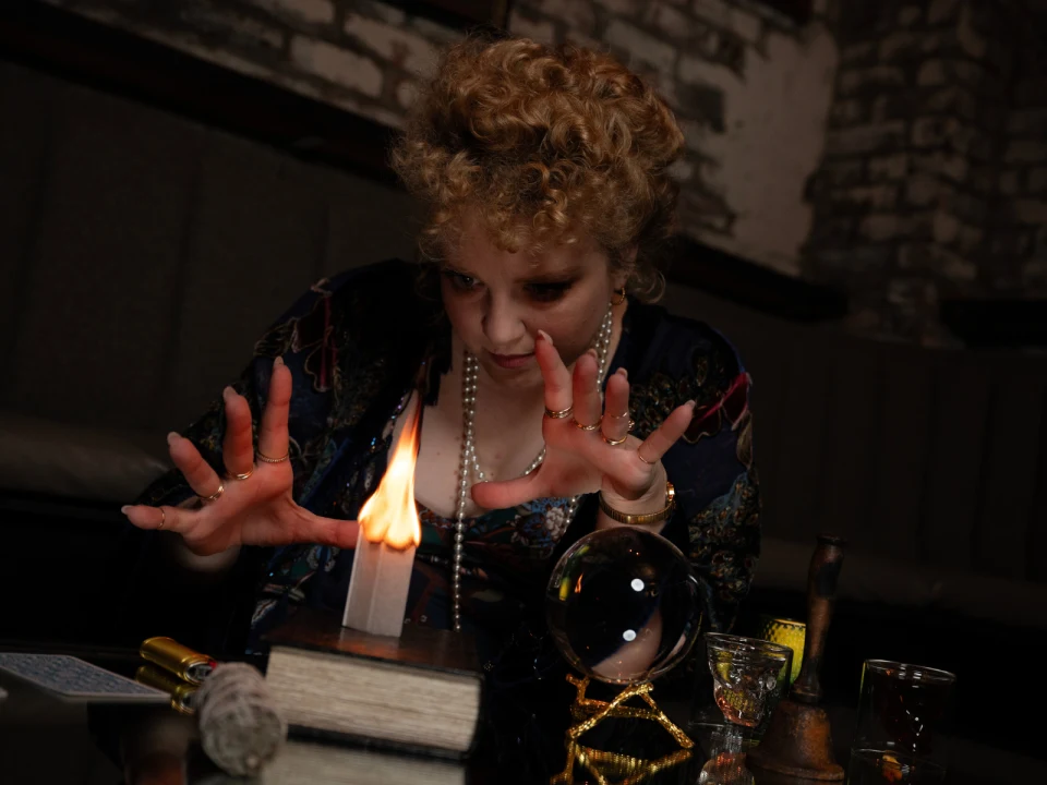 Woman with hands open looking at a candle.