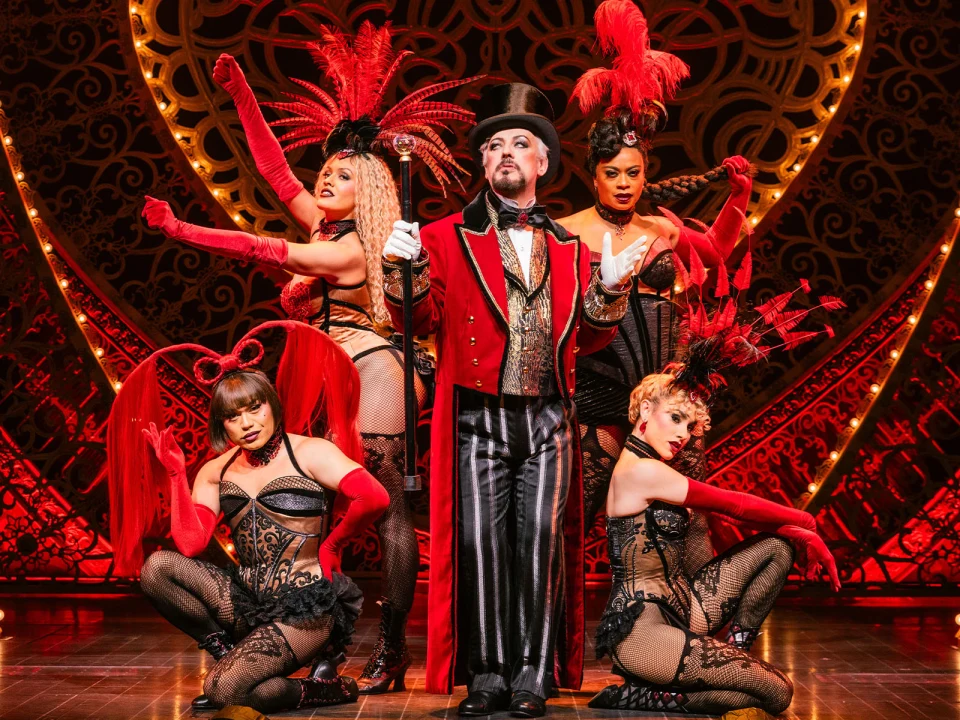 Production shot of Moulin Rouge in New York, with Boy George as Harold Zidler along with the ensemble, posing after a dance performance.