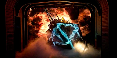 A dramatic stage scene with smoke, lightning effects, a shipwreck set, and a person standing atop the wreck amid an intense, fiery background.