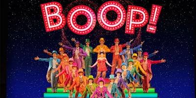 A large group of performers in colorful costumes poses on stage under a bright "BOOP!" sign with illuminated letters.