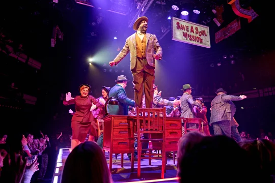 Production image of Guys & Dolls in London featuring ensemble cast and Jonathan Andrew Hume in the role of Nicely Nicely Johnson.