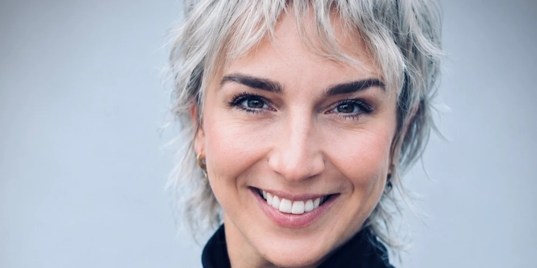 Close-up portrait of a woman with short gray hair smiling at the camera.