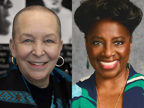Production photo of Angry, Raucous, and Shamelessly Gorgeous in Los Angeles, showing two women smiling in a side-by-side portrait; one has a shaved head and wears hoop earrings, the other has styled hair and also wears earrings.