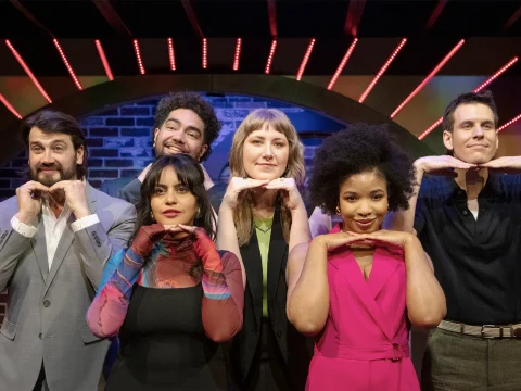 Production shot of The Second City: Ruthless Acts of Kindness in New York, showing ensemble placing their hands on their faces.