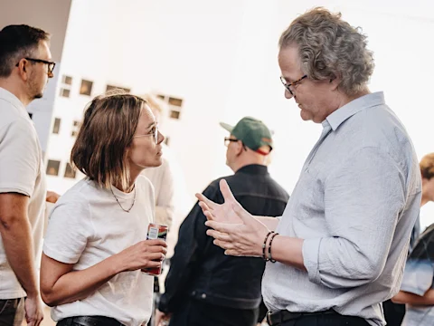 A woman and man in deep conversation, gesturing, during a rehearsal break.