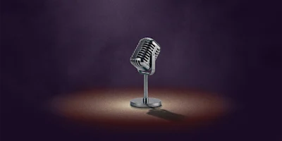 A vintage-style microphone on a stand is spotlighted against a dark, smoky background.