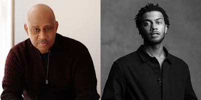 Side-by-side portraits of two men: one older with a shaved head and mustache, wearing a dark sweater; one younger with short locs, wearing a dark shirt, in black and white.