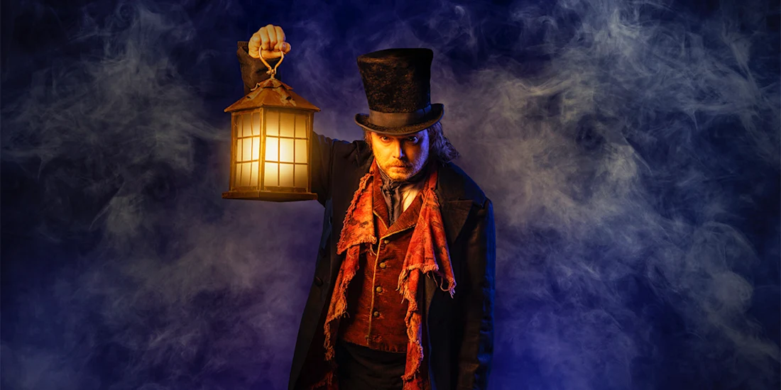 A person in Victorian-era clothing and top hat holds a lit lantern, standing against a background of swirling fog and blue light.