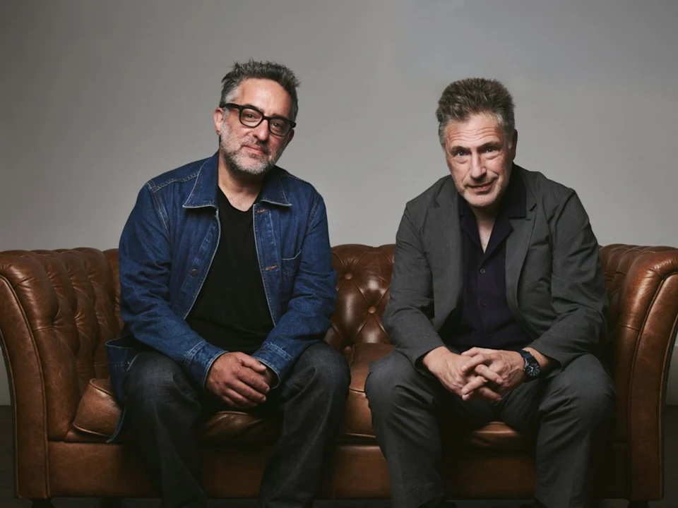 Two men sitting on a leather sofa.