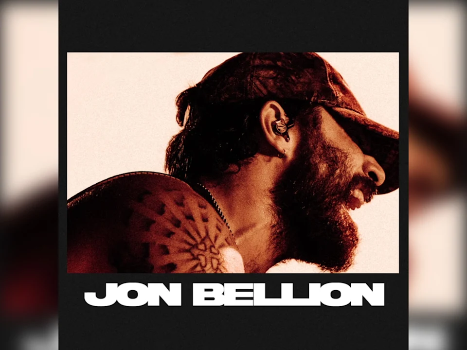 Side view of a bearded man wearing a cap and earpiece, with visible tattoos on his shoulder. Large white text at the bottom reads “JON BELLION.”.