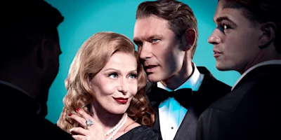 Four formally dressed adults stand closely together; the woman in pearls and red lipstick looks forward while a man in a tuxedo whispers in her ear against a blue background.